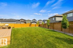 Expansive backyard featuring a manicured lawn, a wood-finish composite deck, and a perimeter wood privacy fence - 