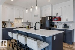 Kitchen featuring a large island with seating, two-tone cabinetry, a built-in kitchen range, and wood-finish flooring - 