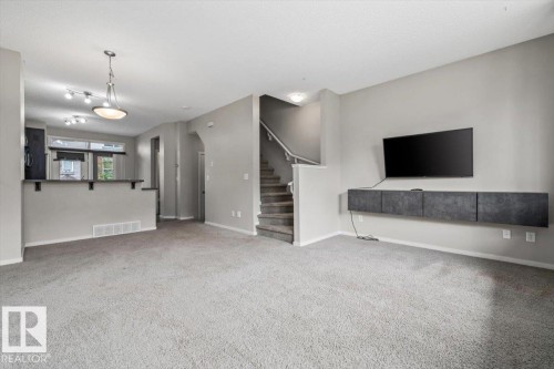 Spacious living area featuring light gray carpet flooring and neutral wall tones - #31 603 Watt Bv Sw, Edmonton, AB - Indoor