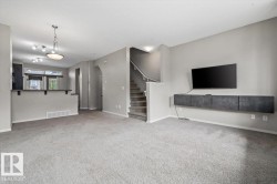 Spacious living area featuring light gray carpet flooring and neutral wall tones - 