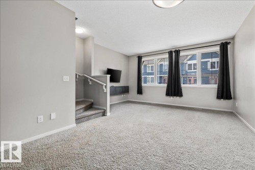 Spacious living area featuring light gray walls and plush gray carpet - #31 603 Watt Bv Sw, Edmonton, AB - Indoor Photo Showing Other Room