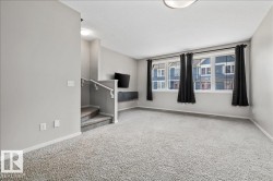 Spacious living area featuring light gray walls and plush gray carpet - 