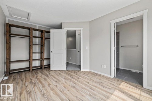Expansive room featuring wood-finish flooring, a built-in open closet system, light gray wall paint, and white trim - #31 603 Watt Bv Sw, Edmonton, AB - Indoor Photo Showing Other Room