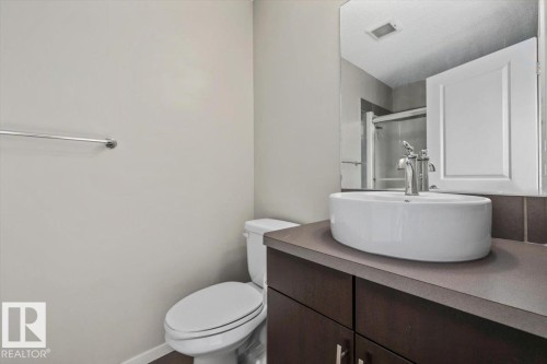Bathroom vanity featuring a vessel sink, single-handle faucet, and dark wood-finish cabinetry - #31 603 Watt Bv Sw, Edmonton, AB - Indoor Photo Showing Bathroom