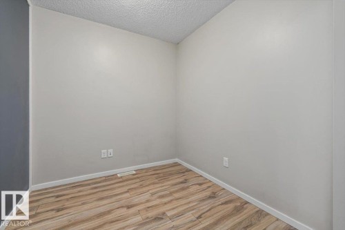 Interior room featuring wood-finish flooring, light gray wall paint, white baseboards, and a textured white ceiling - #31 603 Watt Bv Sw, Edmonton, AB - Indoor Photo Showing Other Room