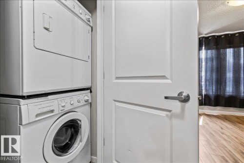 Stackable washer and dryer unit with a classic paneled door and contemporary hardware - #31 603 Watt Bv Sw, Edmonton, AB - Indoor Photo Showing Laundry Room