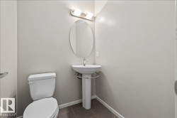 Pedestal sink with a chrome faucet, oval mirror, and wall-mounted light fixture - 