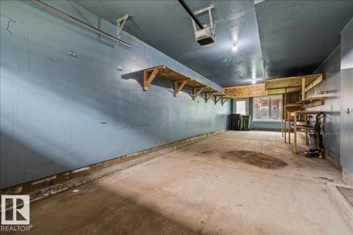 Spacious garage with concrete flooring, overhead garage door opener, and multiple built-in shelving units - #31 603 Watt Bv Sw, Edmonton, AB - Indoor Photo Showing Garage