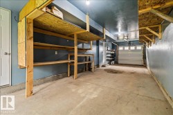 Spacious garage featuring extensive built-in shelving, durable concrete flooring, and an overhead garage door with window inserts - 