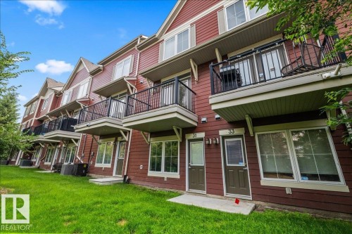Townhome exterior featuring red siding and white trim - #31 603 Watt Bv Sw, Edmonton, AB - Outdoor With Balcony