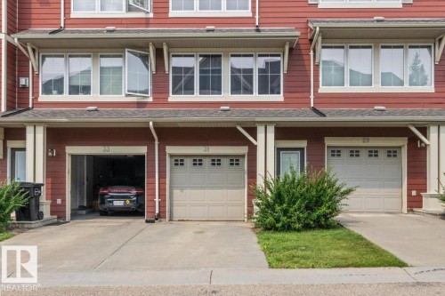 Red siding exterior with white window trim and multiple windows - #31 603 Watt Bv Sw, Edmonton, AB - Outdoor With Facade