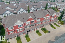 Row of townhomes featuring red exterior siding with white trim accents and individual attached garages - 