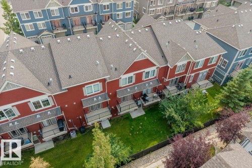 Red-sided multi-family residences featuring individual backyards with green lawns and established landscaping - #31 603 Watt Bv Sw, Edmonton, AB - Outdoor