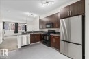 Contemporary kitchen featuring wood-finish cabinetry, stainless steel appliances, and a tiled backsplash - #31 603 Watt Bv Sw, Edmonton, AB  - Indoor Photo Showing Kitchen 