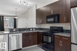 Modern kitchen featuring dark wood-finish cabinetry, stainless steel appliances, and a tiled backsplash - 