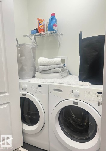 Dedicated laundry area featuring a white front-loading washer and dryer set - 5001 62 Street, Beaumont, AB 