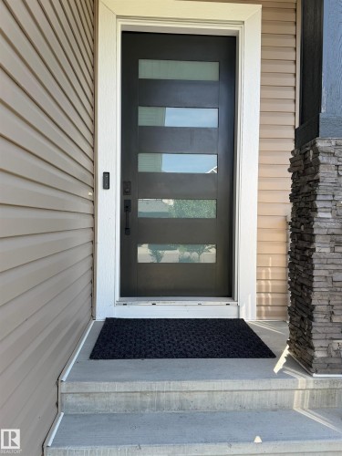 Modern entry door with multiple glass lites and black hardware - 20827 130 Avenue Nw, Edmonton, AB 