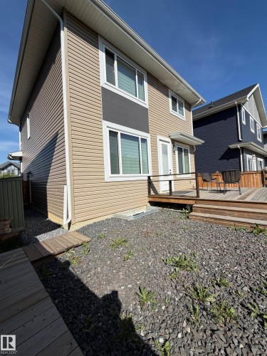 Multi-level exterior with tan and gray siding, white window trim, and a rear deck - 20827 130 Avenue Nw, Edmonton, AB 