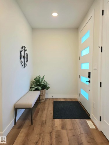 Recessed ceiling lighting, wood-finish flooring, and a modern entry door with horizontal frosted glass inserts - 20827 130 Avenue Nw, Edmonton, AB 