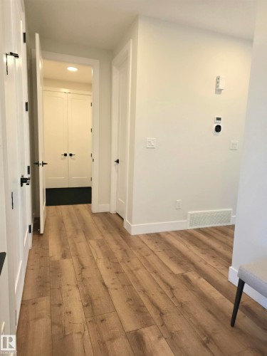 Wood-finish flooring throughout, bright white walls, and matte black door hardware - 20827 130 Avenue Nw, Edmonton, AB 