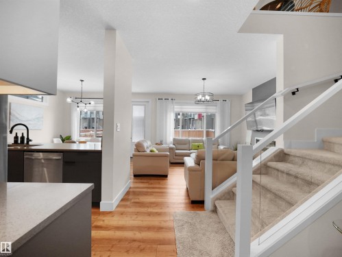 Expansive main living area featuring wood-finish flooring, a contemporary staircase with glass railing, and abundant natural light from multiple windows - 20827 130 Avenue Nw, Edmonton, AB 