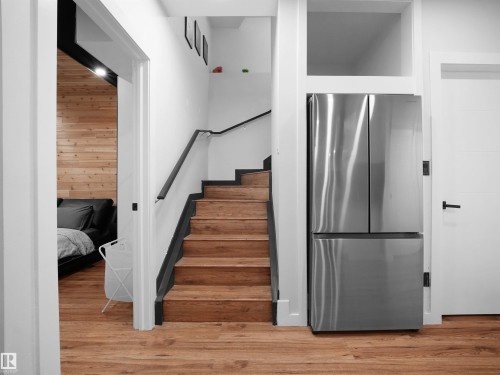Hardwood stairs with a black handrail and white risers - 20827 130 Avenue Nw, Edmonton, AB 