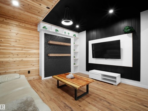 Wood-finish flooring, accent wall with vertical black paneling, built-in shelving, recessed lighting, and a modern pendant light fixture - 20827 130 Avenue Nw, Edmonton, AB 
