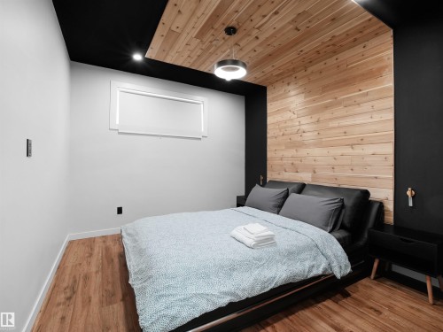 Wood-finish flooring with a horizontal wood-panel accent wall and a black ceiling - 20827 130 Avenue Nw, Edmonton, AB 