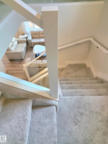 Carpeted staircase with white handrails and clear glass panel railing - 20827 130 Avenue Nw, Edmonton, AB 