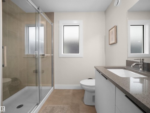 Glass-enclosed shower with tiled surround, single vanity with integrated sink, stone-finish countertop, and built-in cabinetry - 20827 130 Avenue Nw, Edmonton, AB 