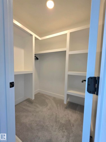 Built-in custom shelving, recessed ceiling lighting, wall-mounted hanging rod, and plush gray carpeting - 20827 130 Avenue Nw, Edmonton, AB 