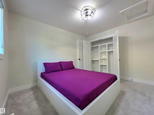 Built-in closet shelving, contemporary ceiling light fixture, white walls, gray carpeting, and a window - 20827 130 Avenue Nw, Edmonton, AB 