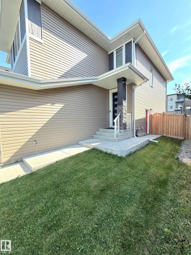 Contemporary exterior with horizontal siding, stone accent pillar, covered entry, and concrete walkway - 20827 130 Avenue Nw, Edmonton, AB 