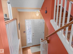 Entryway featuring a white paneled front door with frosted sidelight, wood-finish flooring, and a decorative overhead light fixture - 