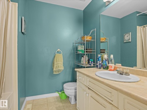 Bathroom featuring an integrated sink with a cream-toned countertop, a full-width mirror, and a vanity with cabinet storage - #15 11717 9B Av Nw, Edmonton, AB - Indoor Photo Showing Bathroom