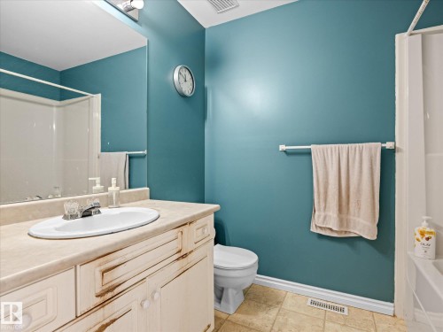 Bathroom featuring a single vanity with an integrated sink, a large mirror, track lighting, and a white tub and shower combination with a sliding glass enclosure - #15 11717 9B Av Nw, Edmonton, AB - Indoor Photo Showing Bathroom