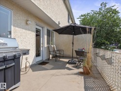 Private patio space featuring a stucco exterior, concrete flooring, and an egress door - 