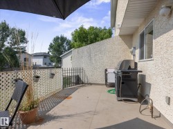 Ground-level patio with stucco exterior, featuring a white lattice fence and black metal gate - 