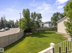 Expansive backyard featuring a manicured lawn, mature trees, and a full perimeter fence - 
