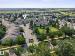 Aerial perspective of a residential complex with multiple multi-story buildings, featuring light-colored exteriors and dark-toned roofs - 