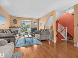 Living area featuring wood-finish flooring, a fireplace with a stone surround, and a bay window - 