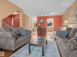 Spacious living area featuring wood-finish flooring, a vibrant accent wall, and recessed lighting - 