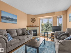 Living area featuring bay windows, a fireplace with a stone surround and wood mantel, wood-finish flooring, and light peach wall paint - 