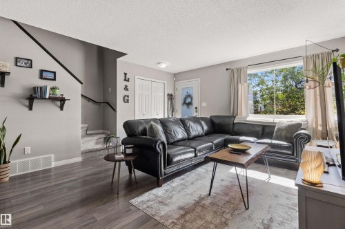 Spacious living area featuring wood-finish flooring, a large window, and light-toned wall finishes - 4306 Prowse Link Link Sw, Edmonton, AB 