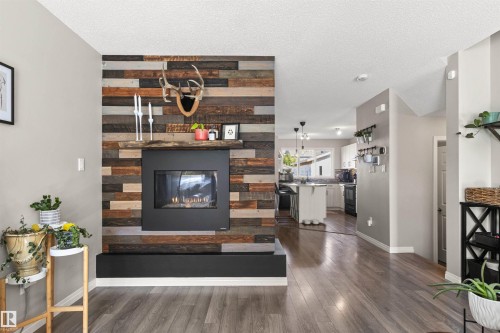 Reclaimed wood-finish fireplace wall with an integrated black hearth and firebox, complemented by wood-finish flooring - 4306 Prowse Link Link Sw, Edmonton, AB 