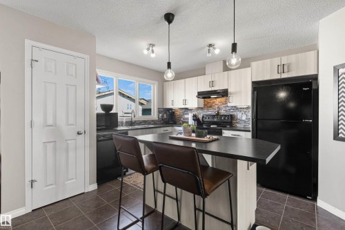 Kitchen featuring integrated appliances, light-toned cabinetry, dark countertops, and a tiled backsplash - 4306 Prowse Link Link Sw, Edmonton, AB 