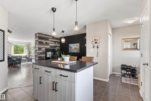 Kitchen island with a dark countertop and light wood-finish cabinetry, complemented by pendant lighting - 4306 Prowse Link Link Sw, Edmonton, AB 