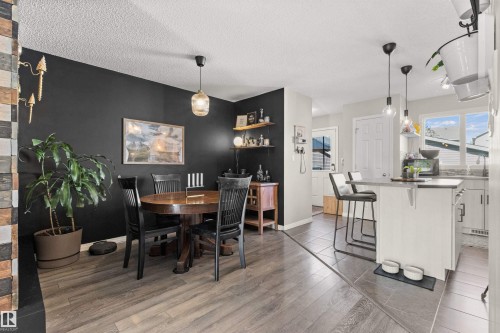 Wood-finish flooring throughout, complemented by a stone-faced accent wall - 4306 Prowse Link Link Sw, Edmonton, AB 
