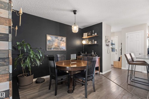 Dining area featuring a circular wood table, pendant light fixture, and wood-finish flooring - 4306 Prowse Link Link Sw, Edmonton, AB 