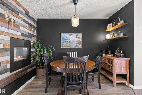 Sophisticated dining space featuring a wood-finish round table, black spindle-back chairs, and rich charcoal accent walls - 4306 Prowse Link Link Sw, Edmonton, AB 